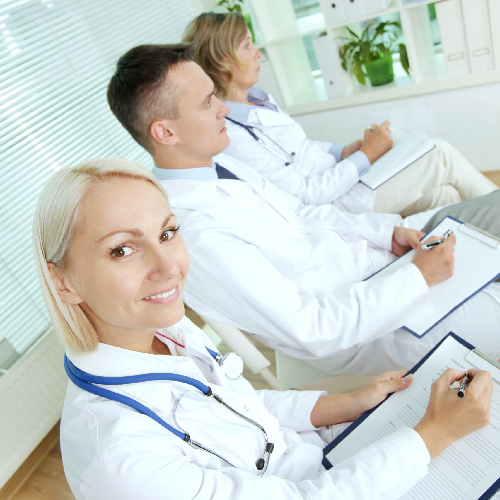 Portrait of three clinicians with clipboards making notes at medical conference